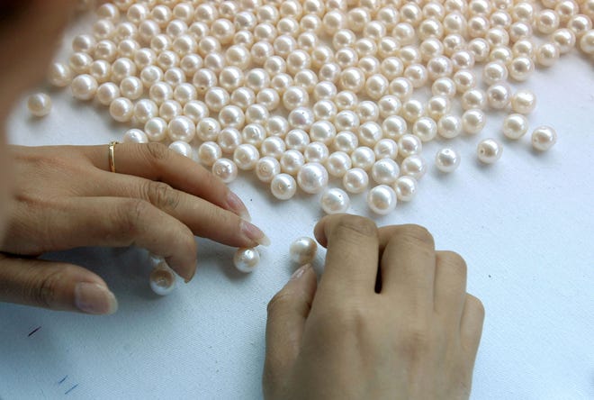 A worker classifies pearls.