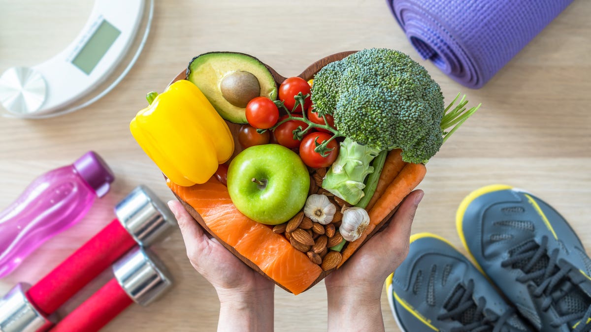 Healthy lifestyle on DASH diet, heart dish with weight scale and sports shoes in fitness center