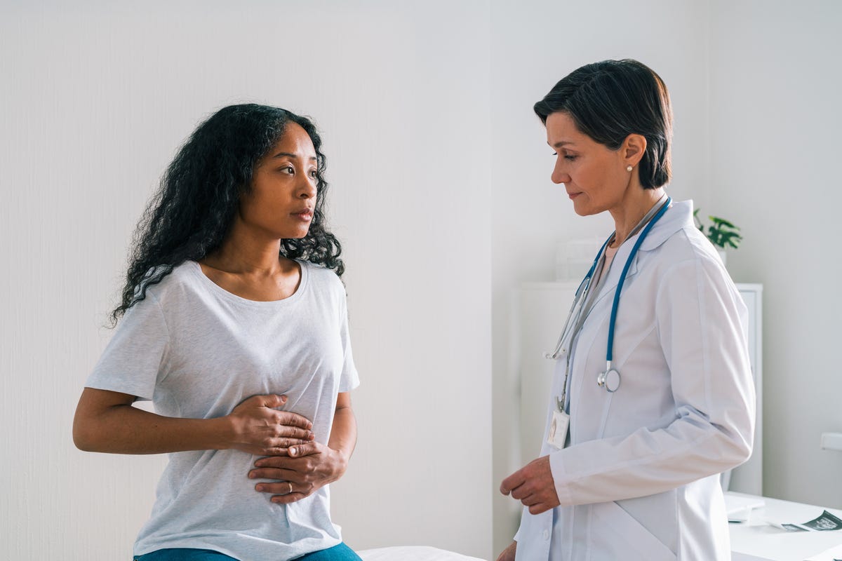 Patient holding their stomach in pain as doctor observes.