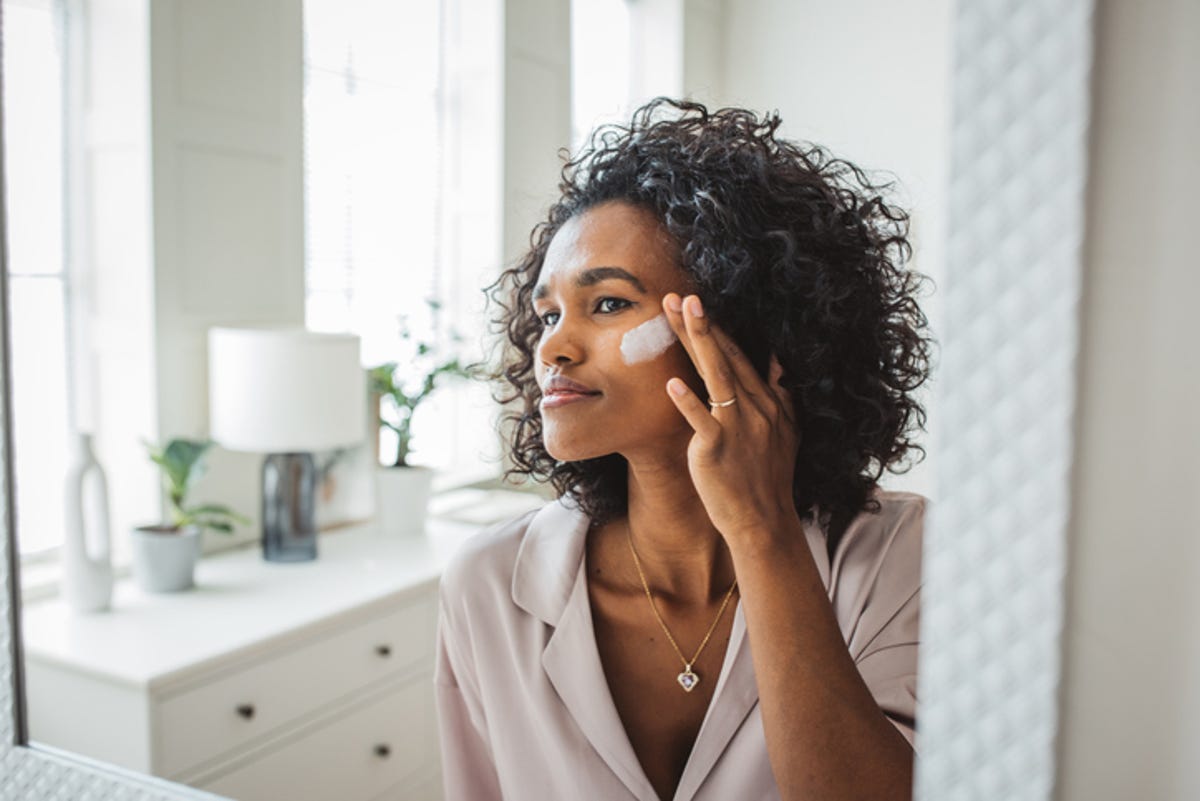 Woman putting moisturizers on her face.