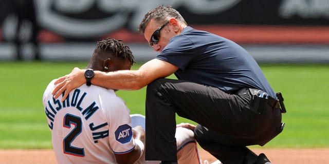 Miami Marlins assistant athletic trainer Ben Potenziano tends to Jazz Chisholm after he was injured attempting to steal second base during the first inning against the Minnesota Twins at loanDepot Park April 5, 2023, in Miami, Fla. 