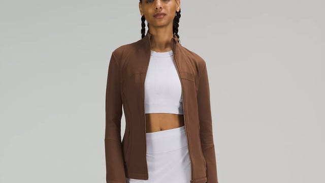 Woman wearing white tank and brown jacket