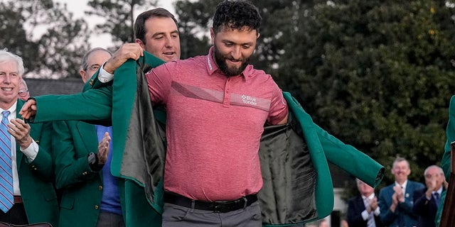 Scottie Scheffler puts the green jacket on Masters winner Jon Rahm at Augusta National Golf Club on Sunday, April 9, 2023.