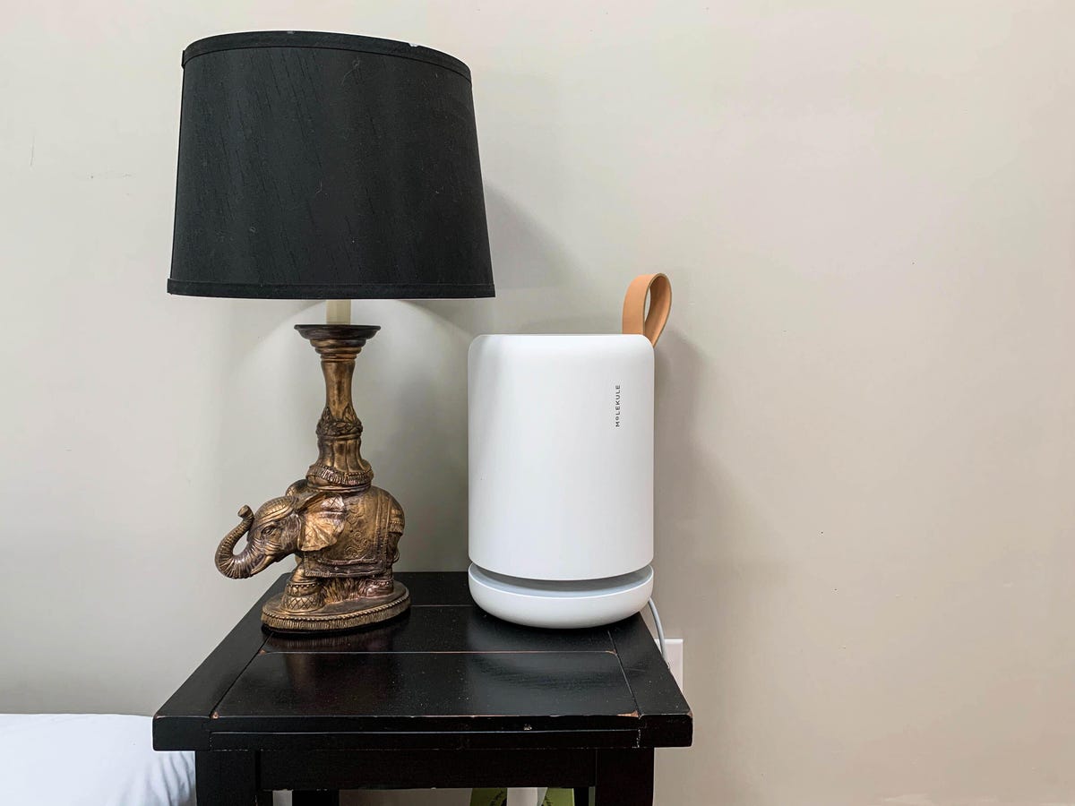 An air purifier on a side table next to a lamp.