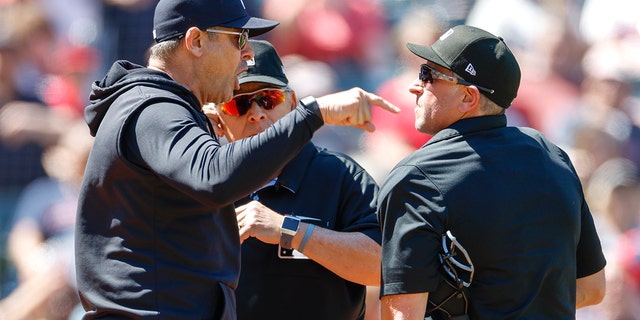 Aaron Boone #17 of the New York Yankees argues a review call with home plate umpires Chris Guccione #68, right, and Larry Vanover #27 after being ejected from the game during the first inning at Progressive Field on April 12, 2023 in Cleveland, Ohio.