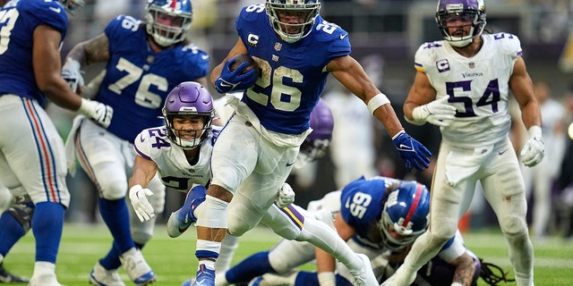 New York Giants running back Saquon Barkley (26) runs from Minnesota Vikings safety Camryn Bynum (24) during a 27-yard touchdown run in the second half of a game Dec. 24, 2022, in Minneapolis.