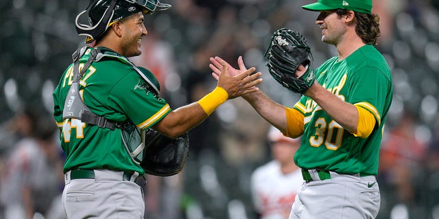 Oakland Athletics catcher Carlos Perez and relief pitcher Chad Smith celebrate their team's win over the Orioles, Wednesday, April 12, 2023, in Baltimore.