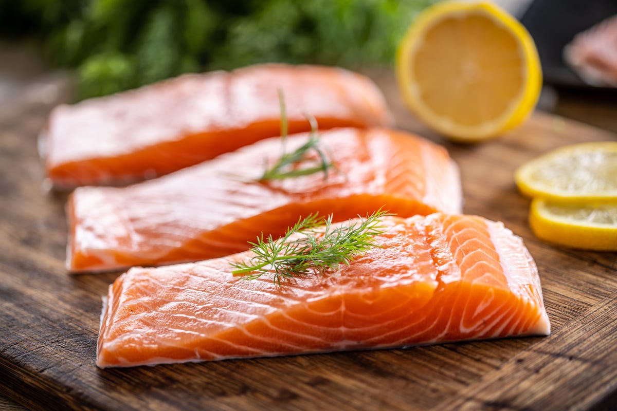 Fresh salmon fillets on a cutting board with lemon.