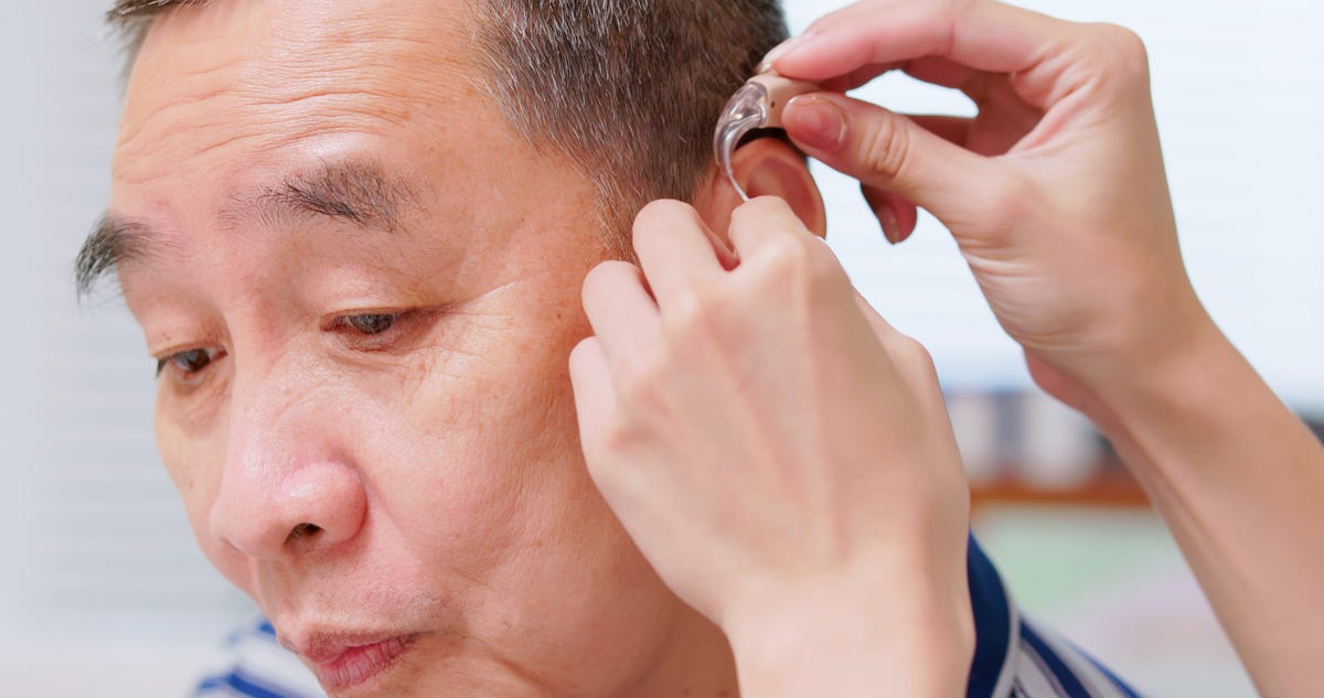 Doctor helps patient wear hearing aids