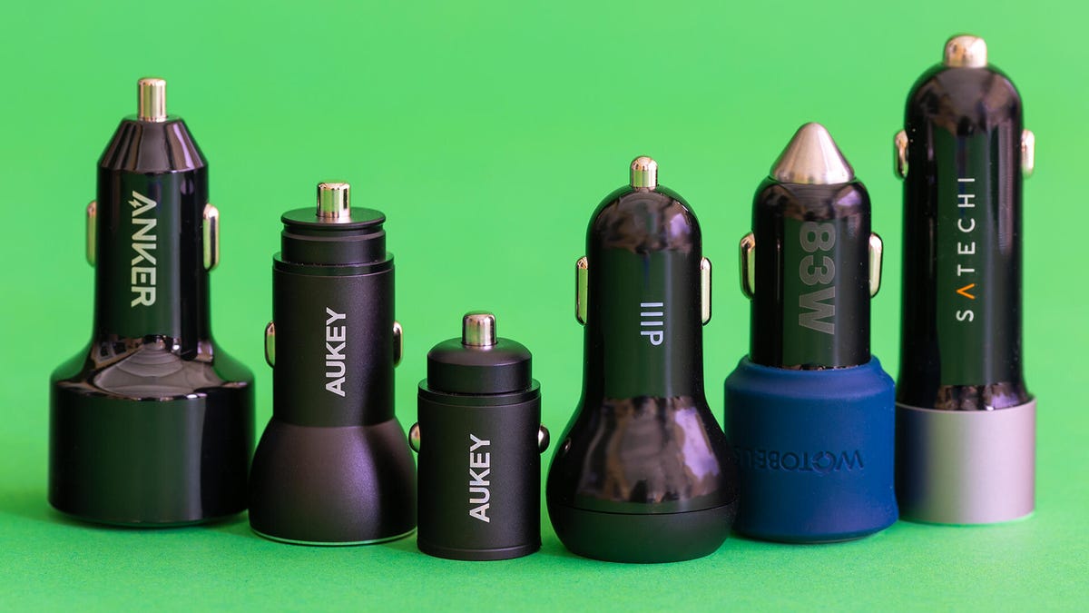 Six 12v USB car charger adapters in a row on a green background.