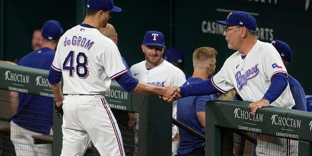 Texas Rangers starting pitcher Jacob deGrom shakes hands with manager Bruce Bochy, right, after working against the Kansas City Royals during the seventh inning of a baseball game Tuesday, April 11, 2023, in Arlington, Texas.