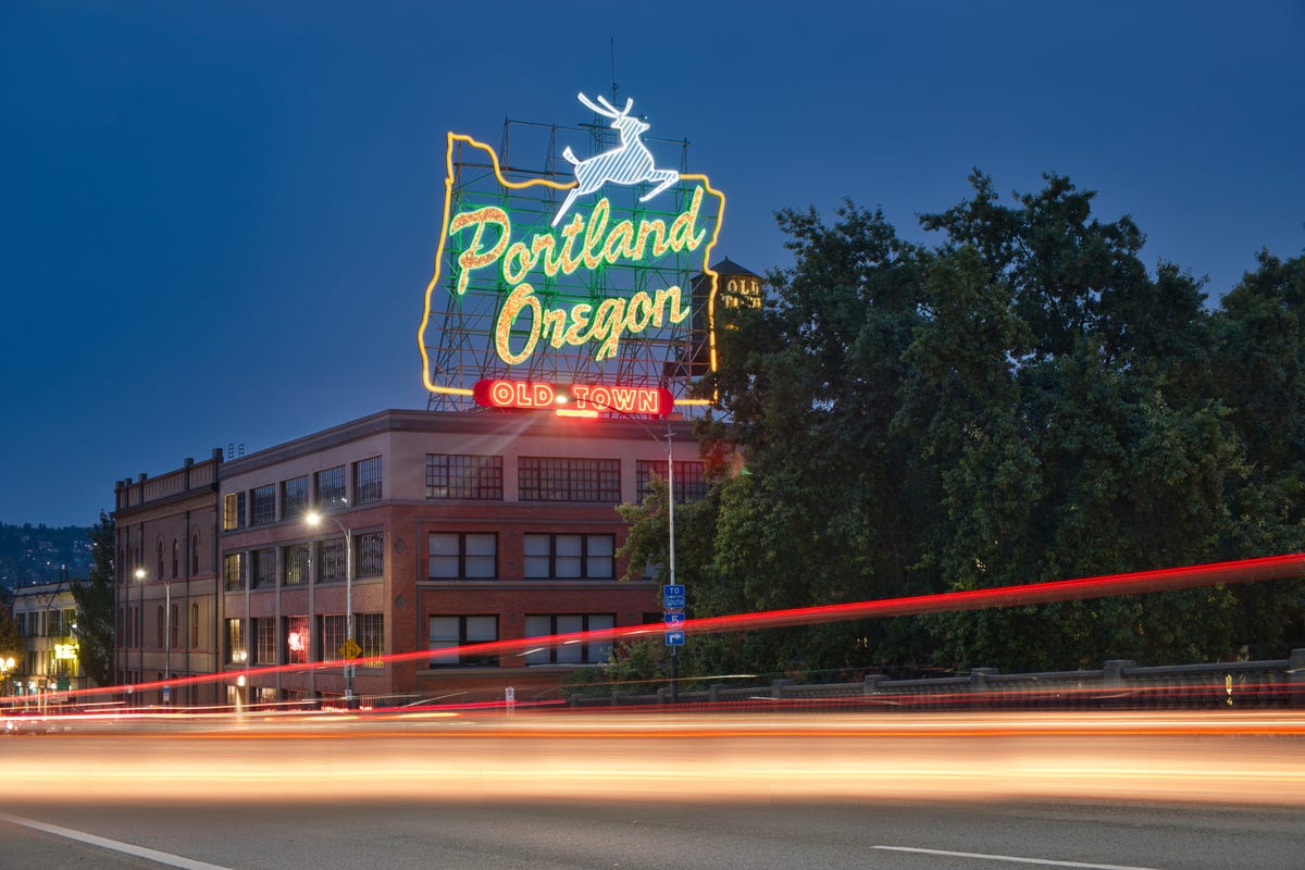 Old town Portland neon sign lit up with the evening sky in the background.