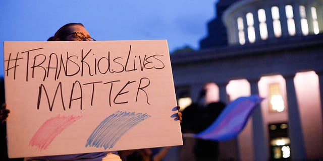 Transgender rights advocate holds up sign