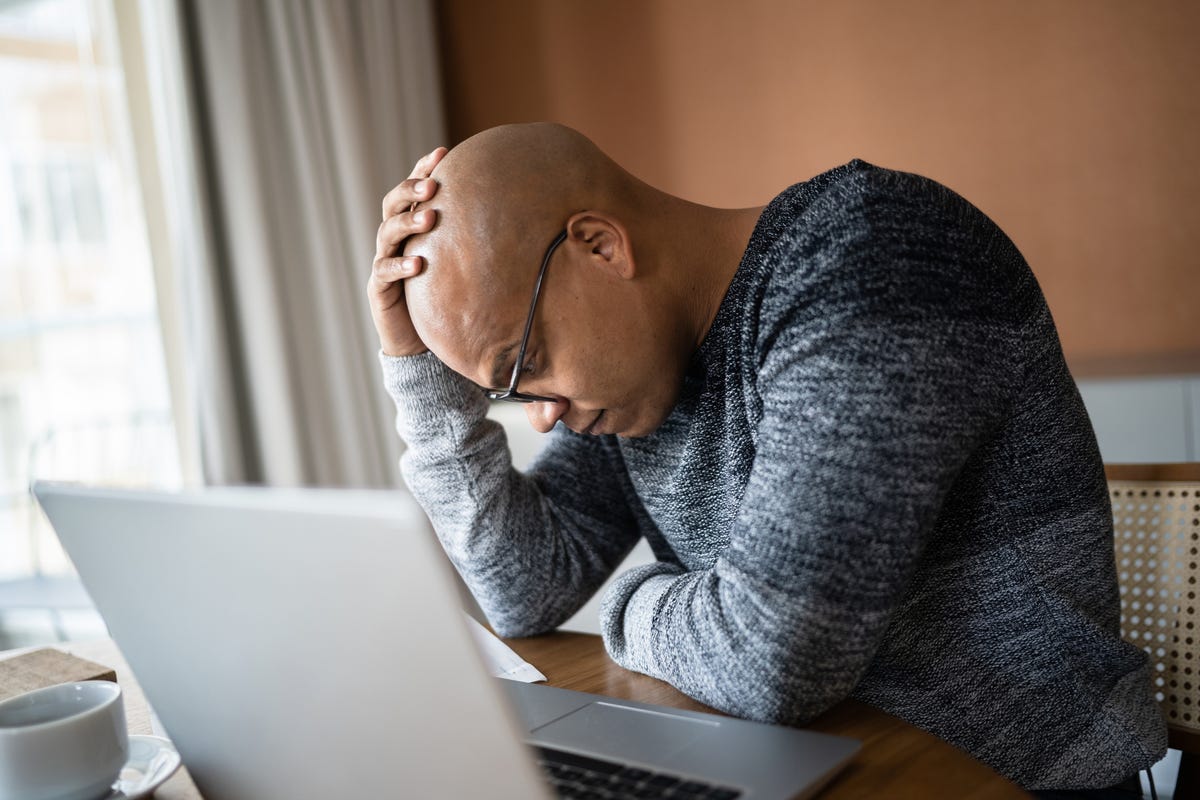 Worried man using laptop working at home.