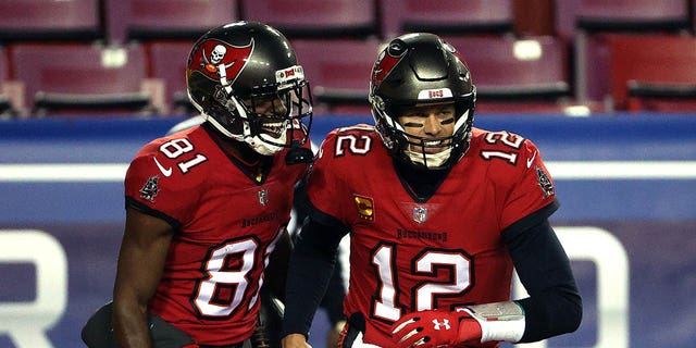 Tampa Bay Buccaneers quarterback Tom Brady, #12, congratulates wide receiver Antonio Brown, #81, after a touchdown during the 1st quarter of the game against the Washington Football Team at FedExField on Jan. 9, 2021 in Landover, Maryland.