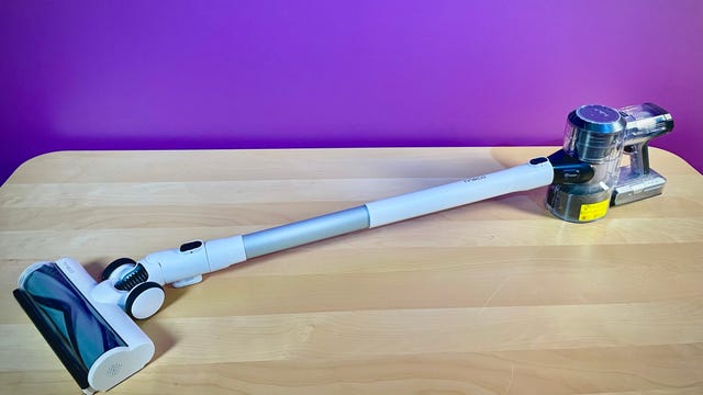 The Tineco Pure One S11 cordless vacuum sits atop a woodgrain table in front of a purple-colored background. It's CNET's top-recommended cordless vacuum of 2023.