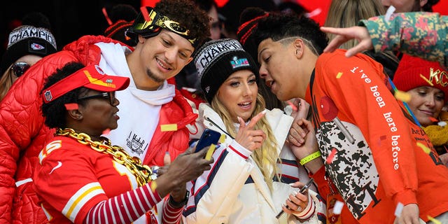 Patrick Mahomes, second from left, looks at a photo with a friend while his wife, Brittany Mahomes, and brother, Jackson Mahomes, right, chat during the Kansas City Chiefs' victory celebration in Kansas City, Mo., Wednesday, Feb. 15, 2023.