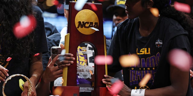 Angel Reese of the LSU Lady Tigers looks at the championship trophy after defeating the Iowa Hawkeyes 102-85 during the NCAA Women's Basketball Tournament championship game at American Airlines Center on April 2, 2023, in Dallas. 