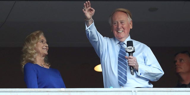 Los Angeles Dodgers broadcaster Vin Scully waves to the crowd alongside his wife Sandra Hunt before the Dodgers take on the Chicago Cubs in game five of the National League Division Series at Dodger Stadium on Oct. 20, 2016 in Los Angeles.