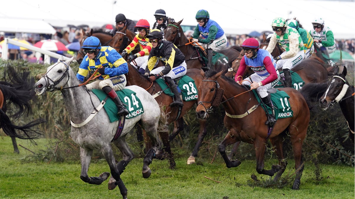 Horses jumping a hurdle at Aintree Racecourse