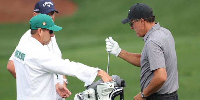 Phil Mickelson of the United States talks with his caddie Tim Mickelson warms up on the practice areaduring a practice round prior to the 2023 Masters Tournament at Augusta National Golf Club on April 04, 2023 in Augusta, Georgia.