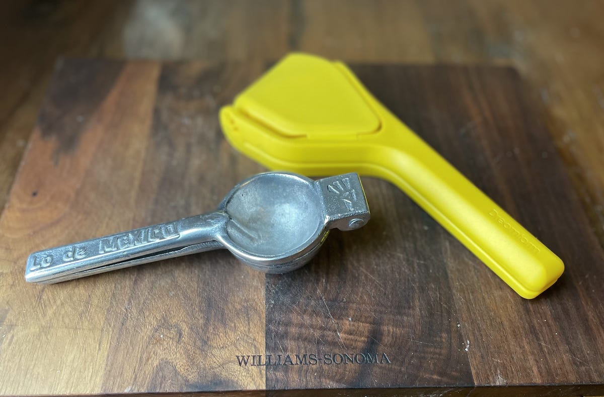 fluicer next to handheld juicer on cutting board