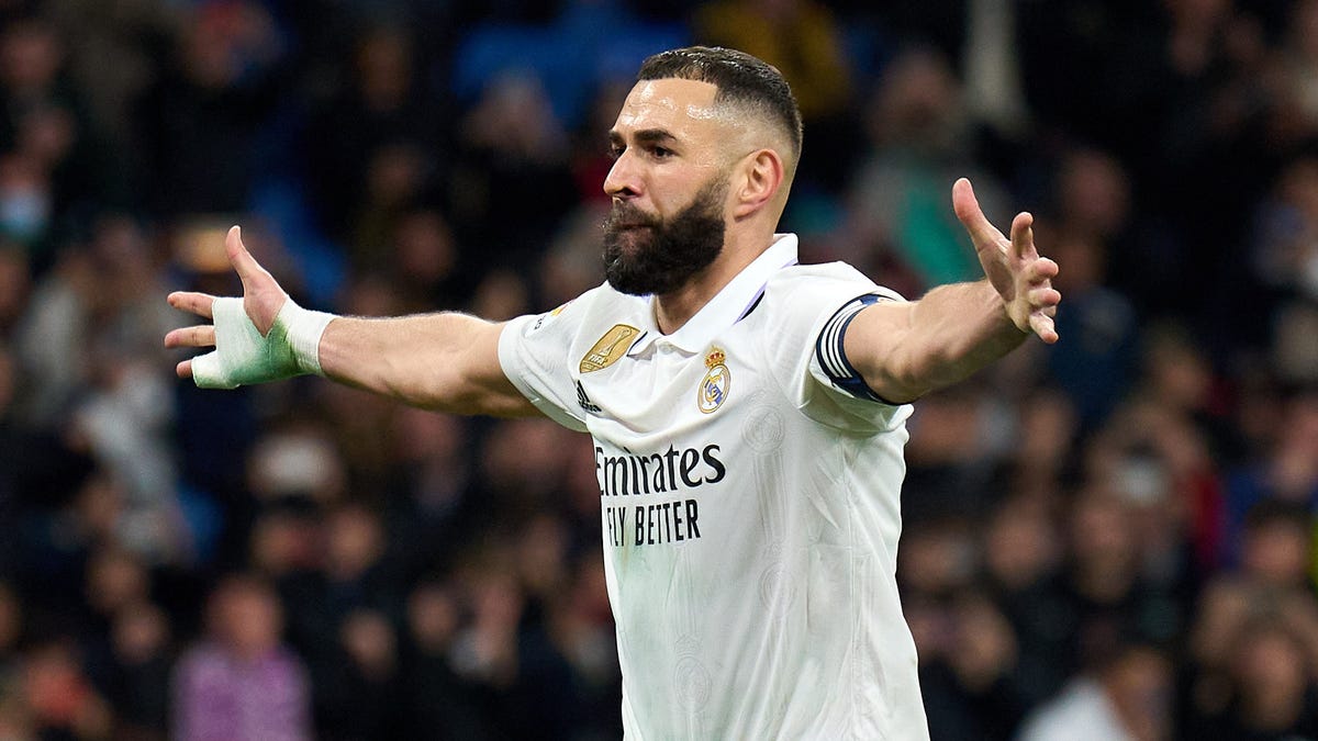 Real Madrid striker celebrates scoring a goal with arms outstretched looking to the right.